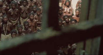 Movie still from “Cobra Verde” (1987), directed by Werner Herzog – A large group of naked african men and women; Extreme Wide shot, High angle