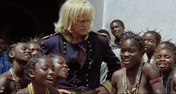 Movie still from “Cobra Verde” (1987), directed by Werner Herzog – A group of people standing next to each other; Medium shot, Over the shoulder angle