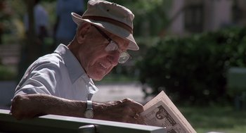 Movie still from “Cocoon” (1985), directed by Ron Howard – An older man reading a newspaper in a park setting; Close Up shot, Low angle