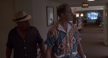 A man wearing a colorful shirt walking down a hall way
