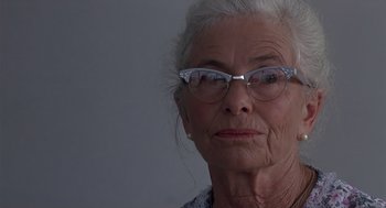 An older woman wearing glasses looking at the camera
