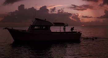 Movie still from “Cocoon” (1985), directed by Ron Howard – Two people standing on the deck of a boat in the ocean; Extreme Wide shot, Low angle