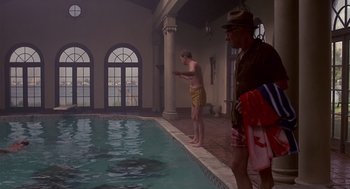 Movie still from “Cocoon” (1985), directed by Ron Howard – Two men standing by a swimming pool in an indoor swimming pool; Wide shot, Over the shoulder angle