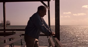 Movie still from “Cocoon” (1985), directed by Ron Howard – An older man leaning on a railing near the ocean; Medium shot, Low angle