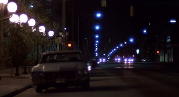 Movie still from “Cocoon” (1985), directed by Ron Howard – A car driving down a street at night; Wide shot, Low angle