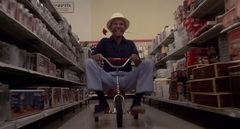 Movie still from “Cocoon” (1985), directed by Ron Howard – An older man riding a tricycle in a store; Wide shot, Low angle
