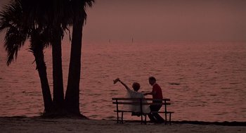 Movie still from “Cocoon” (1985), directed by Ron Howard – Two people sitting on a bench near the ocean; Wide shot, High angle