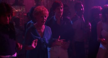 Movie still from “Cocoon” (1985), directed by Ron Howard – A group of people standing in a dark room; Medium shot, Over the shoulder angle
