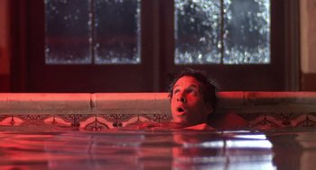 Movie still from “Cocoon” (1985), directed by Ron Howard – A man laying in a pool of water with his mouth open; Medium shot, Low angle