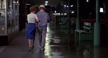 Movie still from “Cocoon” (1985), directed by Ron Howard – A man and a woman walking down a wet sidewalk; Wide shot, Low angle
