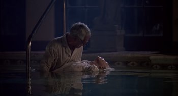 Movie still from “Cocoon” (1985), directed by Ron Howard – An old man and a young girl in a pool of water; Medium shot, High angle