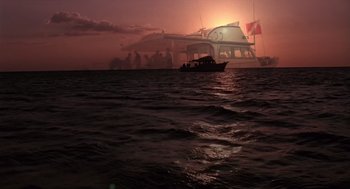 Movie still from “Cocoon” (1985), directed by Ron Howard – A boat in the ocean at sunset with a bridge in the background; Extreme Wide shot, Low angle