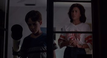 Movie still from “Cocoon” (1985), directed by Ron Howard – A boy and a girl looking at each other through a window; Medium shot, Over the shoulder angle
