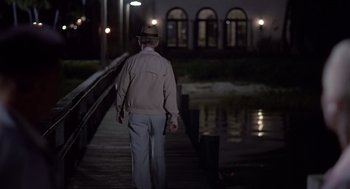 Movie still from “Cocoon” (1985), directed by Ron Howard – An older man walking on a pier at night; Wide shot, Over the shoulder angle