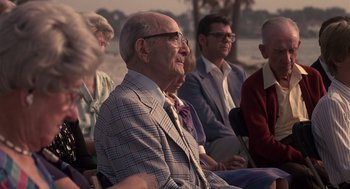 Movie still from “Cocoon” (1985), directed by Ron Howard – An old man sitting in front of a group of older people; Medium shot, Low angle