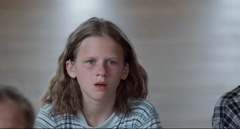 Movie still from “Code Unknown” (2000), directed by Michael Haneke – A young girl with long hair is looking at the camera; Close Up shot, Low angle