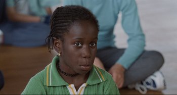 Movie still from “Code Unknown” (2000), directed by Michael Haneke – A person with a person sitting in the background; Close Up shot, High angle