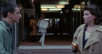 Movie still from “Code Unknown” (2000), directed by Michael Haneke – A woman walking down a street with a bag of shopping; Medium shot, Over the shoulder angle