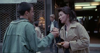 Movie still from “Code Unknown” (2000), directed by Michael Haneke – A man and a woman eating food on the sidewalk; Medium shot, Over the shoulder angle