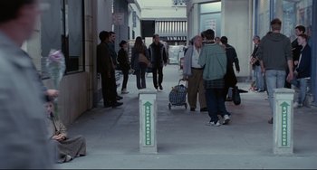 Movie still from “Code Unknown” (2000), directed by Michael Haneke – A group of people walking down a sidewalk; Wide shot, High angle