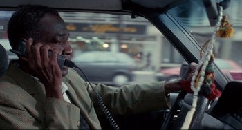 Movie still from “Code Unknown” (2000), directed by Michael Haneke – A man talking on a phone while driving a car; Close Up shot, Over the shoulder angle