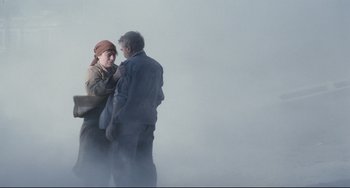 Movie still from “Code Unknown” (2000), directed by Michael Haneke – A man and a woman standing next to each other in the fog; Medium shot, Low angle