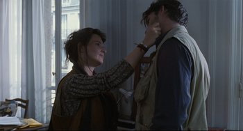 Movie still from “Code Unknown” (2000), directed by Michael Haneke – A woman putting a scarf around a man's neck; Close Up shot, Over the shoulder angle