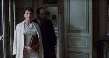 Movie still from “Code Unknown” (2000), directed by Michael Haneke – A man and a woman standing next to each other in a room; Medium shot, Low angle