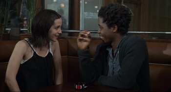 Movie still from “Code Unknown” (2000), directed by Michael Haneke – A man and a woman sitting at a table talking to each other; Medium shot, Over the shoulder angle