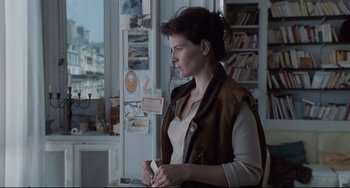 Movie still from “Code Unknown” (2000), directed by Michael Haneke – A woman standing in front of a window; Medium shot, Over the shoulder angle