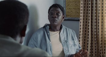 Movie still from “Code Unknown” (2000), directed by Michael Haneke – A man with a shaved head looking into a mirror; Close Up shot, Over the shoulder angle