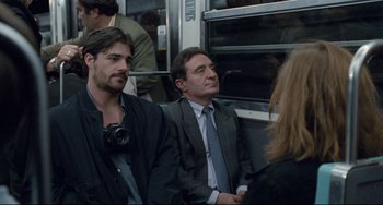 Movie still from “Code Unknown” (2000), directed by Michael Haneke – Two men and a woman are sitting on a bus; Medium shot, Over the shoulder angle