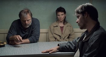 Movie still from “Code Unknown” (2000), directed by Michael Haneke – A group of people sitting around a table; Medium shot, Over the shoulder angle