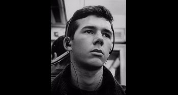 Movie still from “Code Unknown” (2000), directed by Michael Haneke – A young man wearing headphones while standing in a room; Close Up shot, Low angle