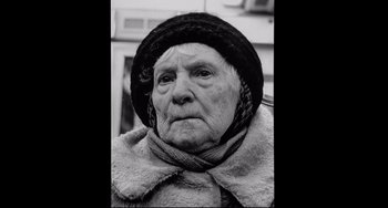 Movie still from “Code Unknown” (2000), directed by Michael Haneke – An old woman wearing a hat and a fur coat; Close Up shot, Low angle