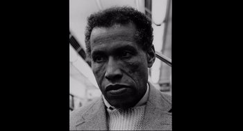 Movie still from “Code Unknown” (2000), directed by Michael Haneke – A black and white photo of a man in a suit; Close Up shot, Low angle