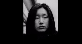 Movie still from “Code Unknown” (2000), directed by Michael Haneke – A black - and - white photo of a woman with long hair; Close Up shot, Low angle