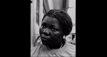 Movie still from “Code Unknown” (2000), directed by Michael Haneke – A black and white photo of a woman with braids; Close Up shot, High angle