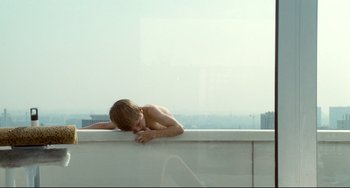 Movie still from “Code Unknown” (2000), directed by Michael Haneke – A young boy laying on a ledge looking out at the city; Wide shot, High angle