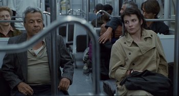 Movie still from “Code Unknown” (2000), directed by Michael Haneke – A man and a woman are sitting on a train; Medium shot, Over the shoulder angle