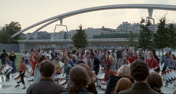 Movie still from “Code Unknown” (2000), directed by Michael Haneke – A group of people sitting on top of drums; Extreme Wide shot, High angle