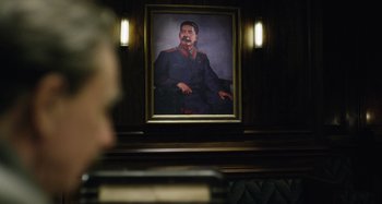 Movie still from “The Death of Stalin” (2017), directed by Armando Iannucci – A portrait of stalin hangs on the wall; Medium shot, Over the shoulder angle