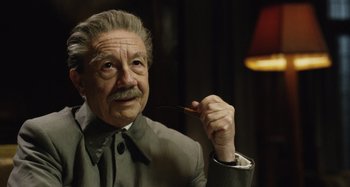 Movie still from “The Death of Stalin” (2017), directed by Armando Iannucci – An older man in a suit and tie holding a fork; Close Up shot, Low angle