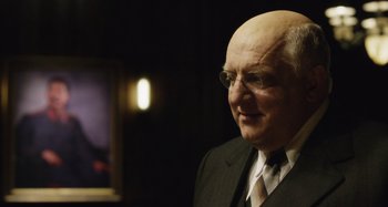 Movie still from “The Death of Stalin” (2017), directed by Armando Iannucci – An older man wearing a suit and tie; Close Up shot, Over the shoulder angle