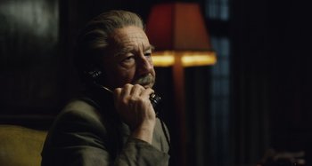 Movie still from “The Death of Stalin” (2017), directed by Armando Iannucci – An older man talking on a phone while standing in front of a lamp; Close Up shot, Low angle
