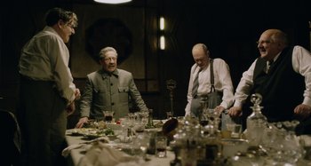 Movie still from “The Death of Stalin” (2017), directed by Armando Iannucci – A group of people sitting around a table with food on it; Medium shot, Over the shoulder angle