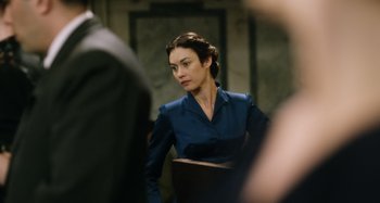 Movie still from “The Death of Stalin” (2017), directed by Armando Iannucci – A woman in a blue dress is sitting down; Medium shot, Over the shoulder angle