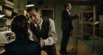 Movie still from “The Death of Stalin” (2017), directed by Armando Iannucci – A man in a suit and tie standing next to a woman; Medium shot, Over the shoulder angle