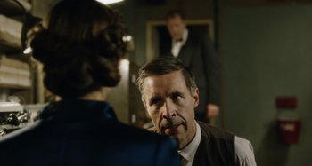 Movie still from “The Death of Stalin” (2017), directed by Armando Iannucci – A man in a suit and tie talking to another man in a suit and tie; Medium shot, Over the shoulder angle