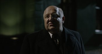Movie still from “The Death of Stalin” (2017), directed by Armando Iannucci – An older man wearing a suit and tie; Close Up shot, Over the shoulder angle